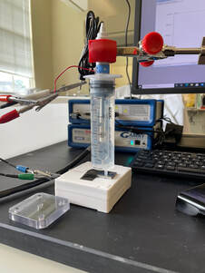 Syringe cell setup in front of a stack of two potentiostats.